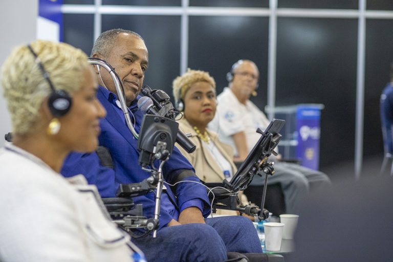 Público com e sem deficiência assiste a uma palestra sobre inclusão no congresso Reatech. Homem em cadeira de rodas no centro.